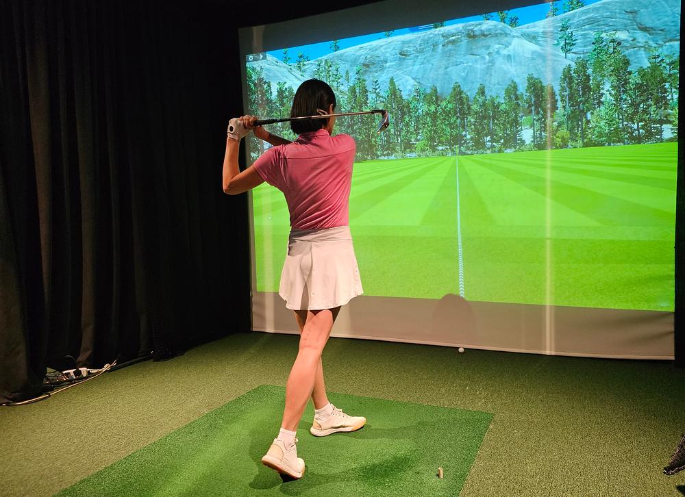 Golfer at the top of the backswing in a home golf simulator room