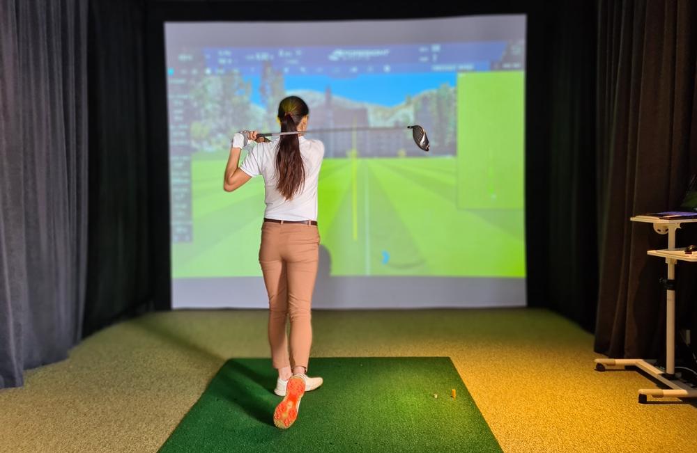 Golfer mid backswing in a residential golf simulator room